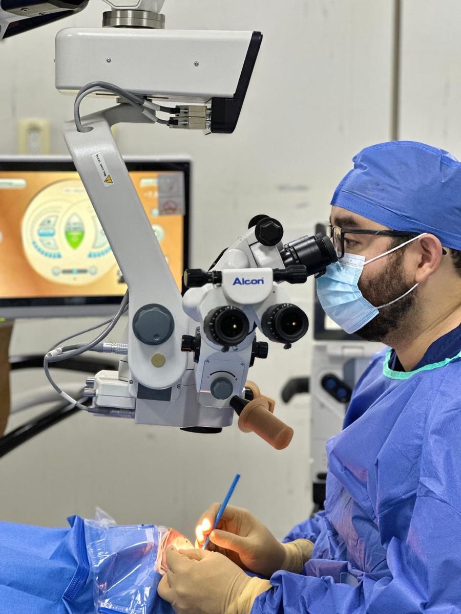 El doctor operando a través del microscopio quirúrgico Alcon, con la pantalla del equipo de facoemulsificación al fondo